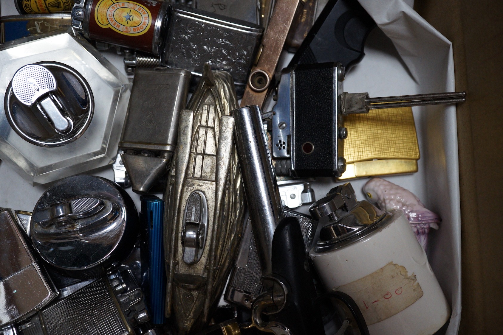 A collection of lighters including some novelty examples such as a percussion cup pistol, a KKW lighter camera, and a spy camera lighter